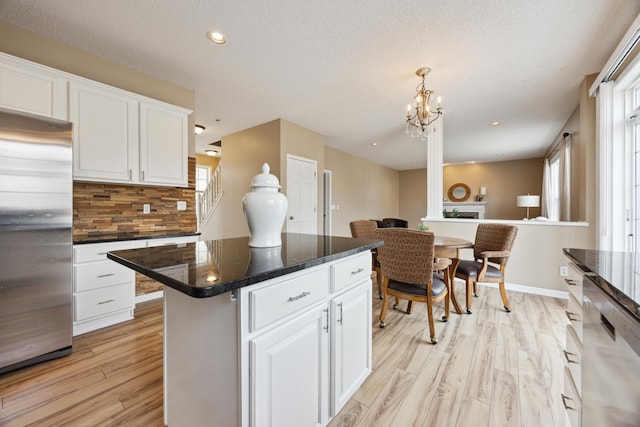 kitchen with stainless steel appliances, white cabinetry, a healthy amount of sunlight, backsplash, and light wood finished floors