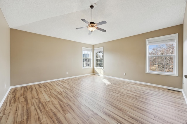 unfurnished room with lofted ceiling, light wood finished floors, a ceiling fan, and baseboards