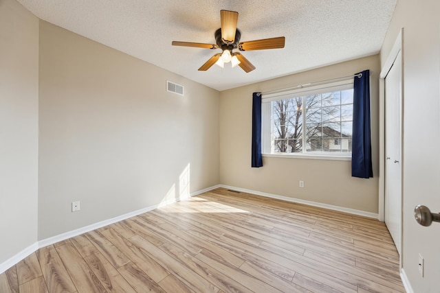 unfurnished bedroom with a textured ceiling, light wood-type flooring, visible vents, and baseboards