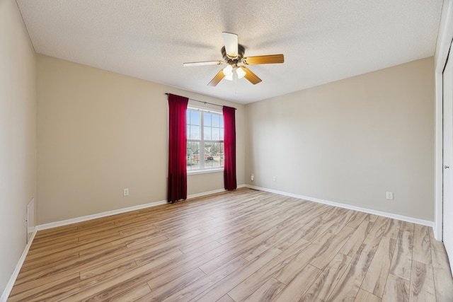 spare room featuring ceiling fan, a textured ceiling, light wood-style flooring, and baseboards