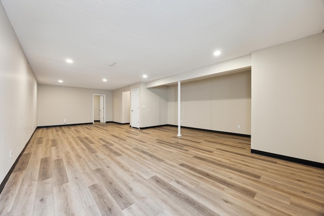 finished basement featuring a textured ceiling, light wood-type flooring, baseboards, and recessed lighting