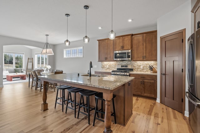 kitchen featuring appliances with stainless steel finishes, pendant lighting, sink, a kitchen breakfast bar, and a center island with sink