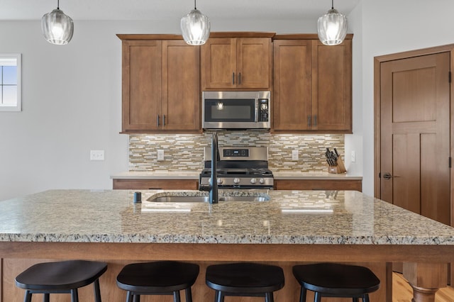 kitchen featuring appliances with stainless steel finishes, a center island with sink, and backsplash