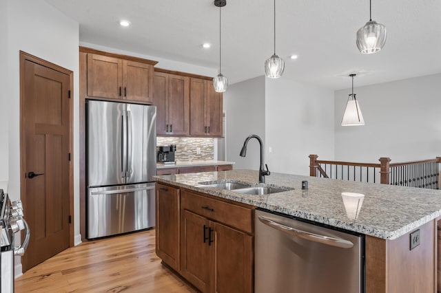 kitchen featuring stainless steel appliances, an island with sink, hanging light fixtures, and sink