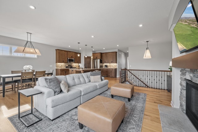 living room featuring sink, a stone fireplace, and light wood-type flooring