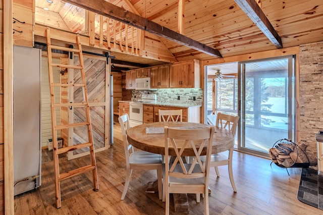 dining room featuring lofted ceiling with beams, a barn door, and wooden ceiling