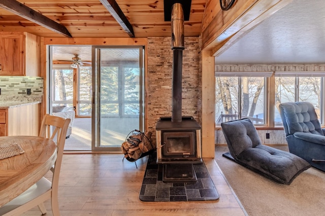 living room featuring wood ceiling, plenty of natural light, wooden walls, and a wood stove