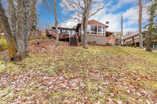 back of house with a wooden deck and a lawn