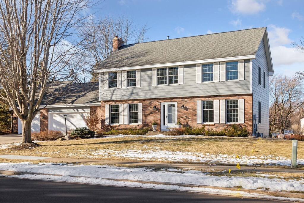 2493 Bridgeview Ct, Mendota Heights, MN 55120 - colonial-style house with brick siding, a garage, roof with shingles, and a chimney