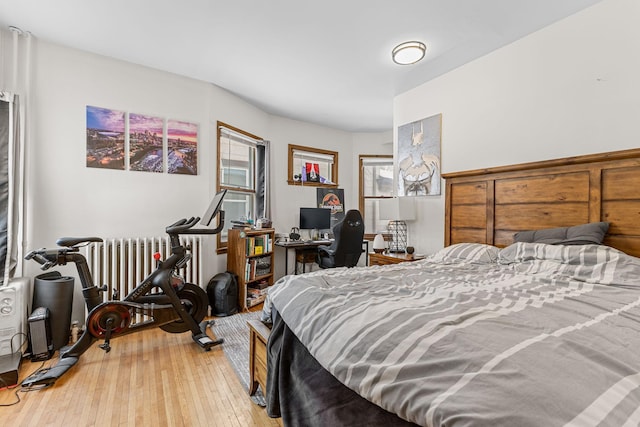 bedroom with radiator heating unit and light wood finished floors