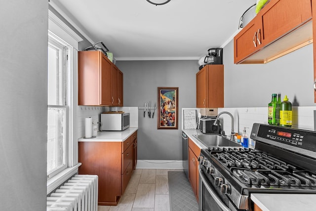 kitchen with brown cabinets, radiator, light countertops, appliances with stainless steel finishes, and a sink