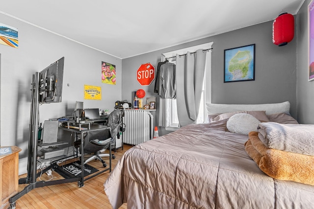 bedroom featuring radiator, crown molding, and wood finished floors