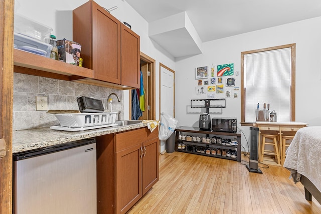 kitchen featuring light stone counters, tasteful backsplash, brown cabinets, and stainless steel refrigerator