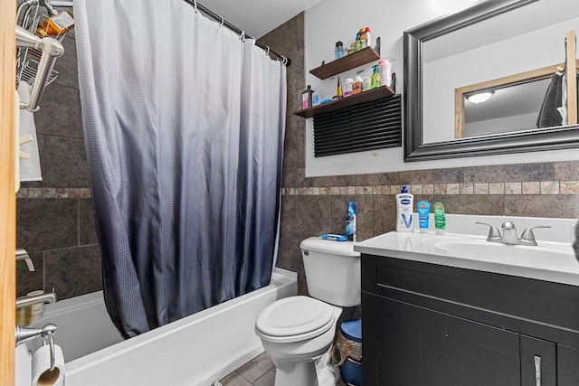 full bathroom with toilet, a wainscoted wall, shower / bath combination with curtain, vanity, and tile walls