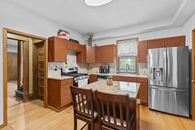 2707 Fremont Ave S, Minneapolis, MN 55408 - kitchen featuring appliances with stainless steel finishes, light wood-type flooring, tasteful backsplash, and light stone counters