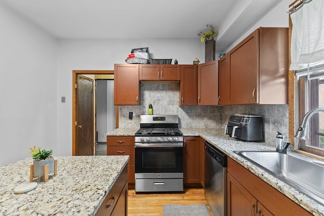 2707 Fremont Ave S, Minneapolis, MN 55408 - kitchen featuring stainless steel appliances, backsplash, light wood-style flooring, and light stone countertops