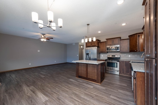 kitchen featuring sink, a center island, appliances with stainless steel finishes, pendant lighting, and backsplash