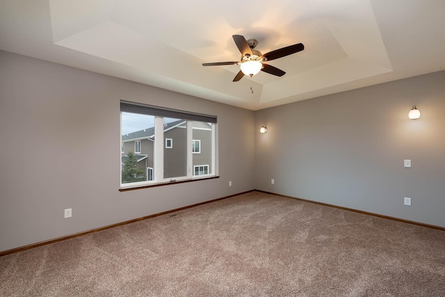 spare room featuring a tray ceiling, ceiling fan, and carpet