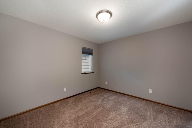 carpeted empty room featuring a textured ceiling