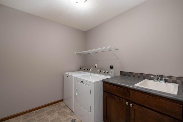 washroom with cabinets, sink, washing machine and dryer, and a textured ceiling