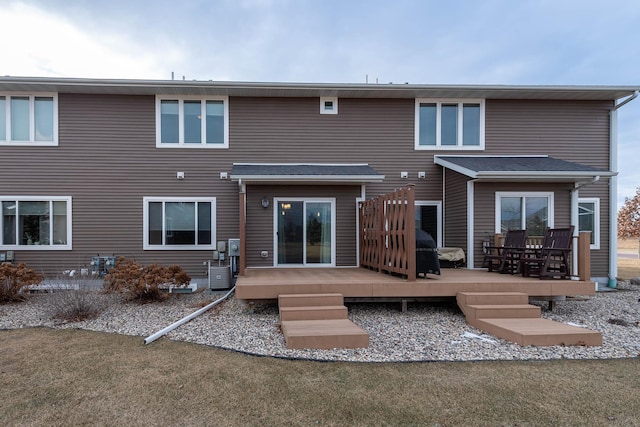 rear view of property featuring a wooden deck and a lawn