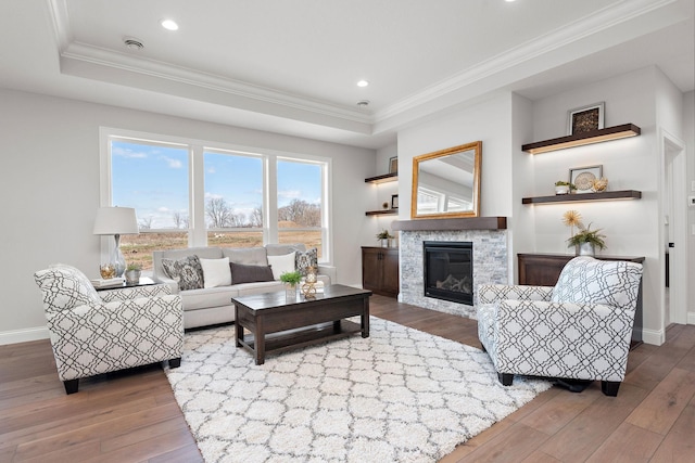 living room with hardwood / wood-style floors, a tray ceiling, and ornamental molding