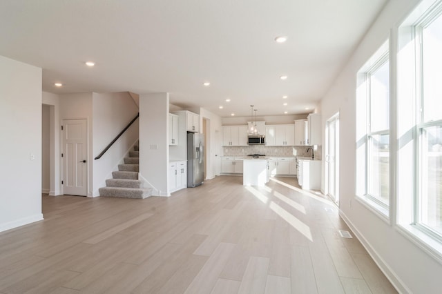 unfurnished living room with sink and light hardwood / wood-style flooring