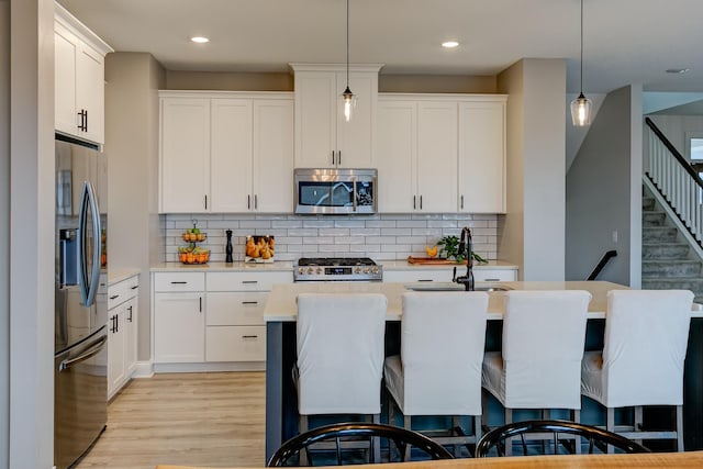 kitchen featuring stainless steel appliances, white cabinets, and decorative light fixtures