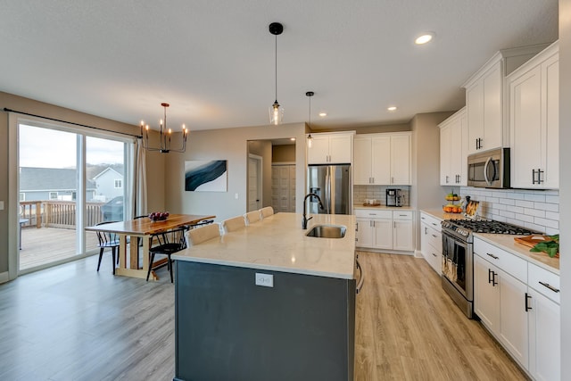 kitchen with sink, decorative light fixtures, white cabinets, and appliances with stainless steel finishes