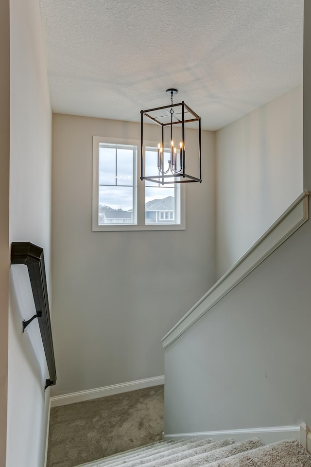 stairs featuring a chandelier, a textured ceiling, and carpet flooring