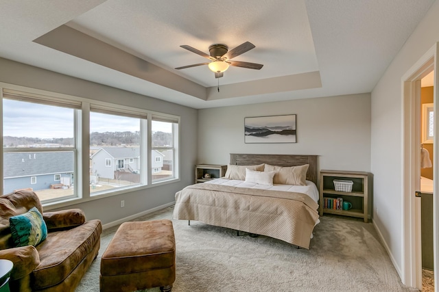 bedroom with a raised ceiling, ceiling fan, and carpet flooring