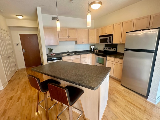 kitchen with pendant lighting, sink, a breakfast bar area, stainless steel appliances, and light brown cabinets