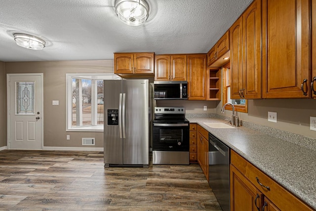 kitchen with sink, dark wood-type flooring, a textured ceiling, and appliances with stainless steel finishes