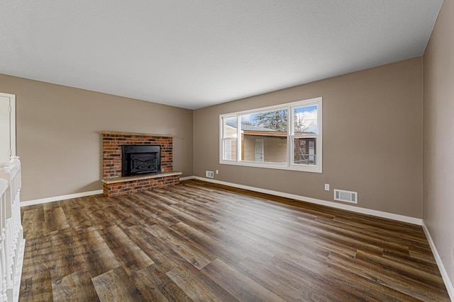 unfurnished living room featuring dark wood-type flooring and a brick fireplace