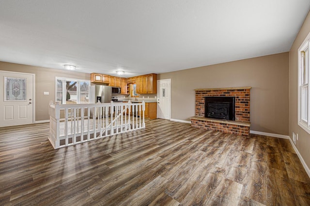 unfurnished living room featuring wood-type flooring and a brick fireplace