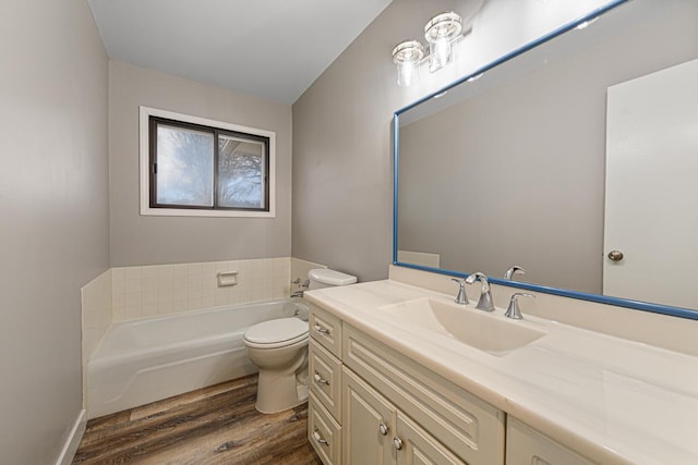 bathroom with hardwood / wood-style flooring, vanity, a tub, and toilet