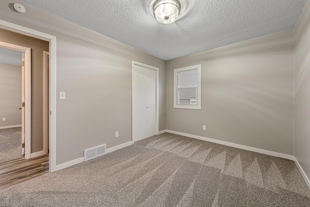 carpeted spare room with a textured ceiling