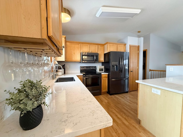 kitchen with light wood-type flooring, lofted ceiling, light stone counters, black appliances, and a sink