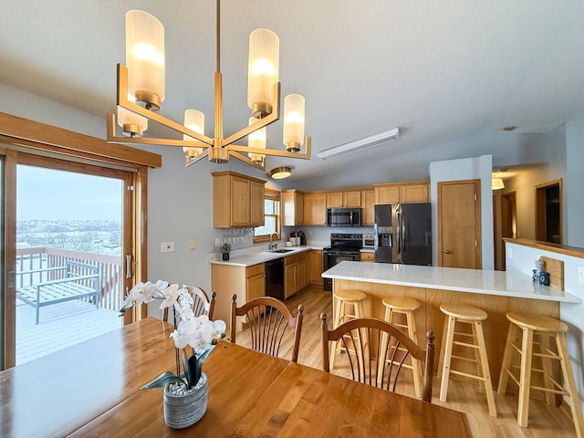 kitchen with black appliances, light wood-style flooring, a peninsula, and light countertops