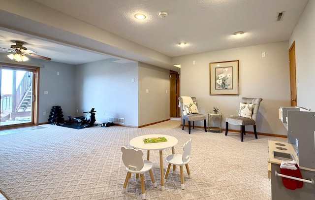 sitting room featuring light carpet, visible vents, a textured ceiling, and baseboards