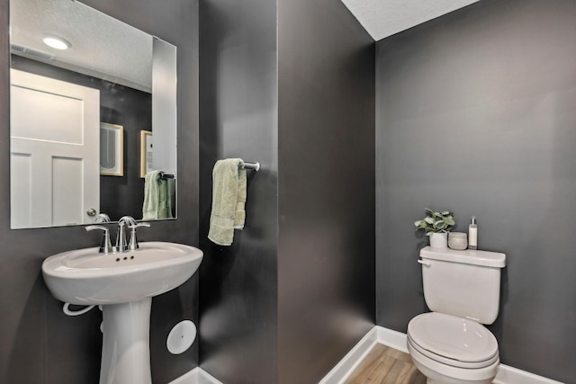 bathroom featuring hardwood / wood-style floors, a textured ceiling, and toilet