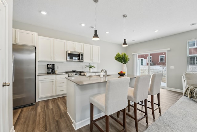 kitchen with appliances with stainless steel finishes, decorative light fixtures, sink, and white cabinets