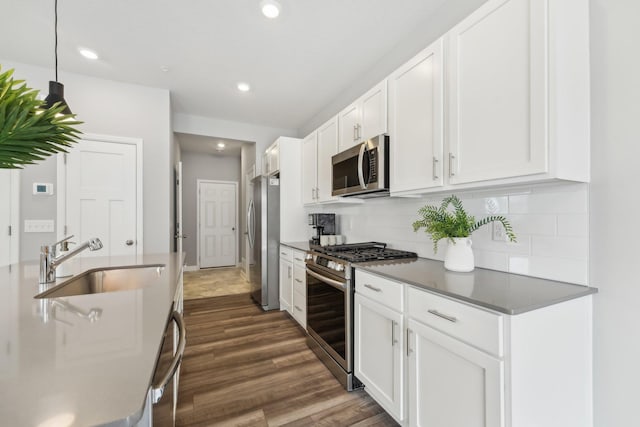 kitchen with white cabinetry, sink, backsplash, hanging light fixtures, and stainless steel appliances