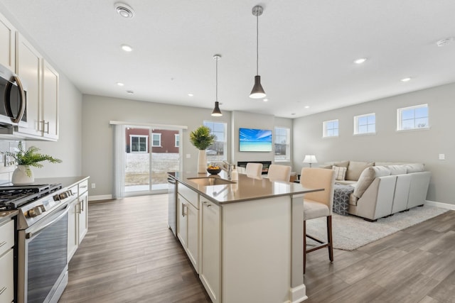 kitchen with a breakfast bar, hanging light fixtures, a kitchen island, stainless steel appliances, and white cabinets