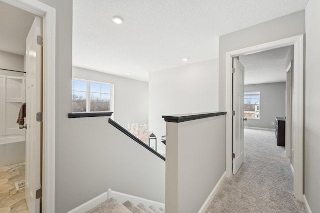 hallway featuring light carpet and a textured ceiling