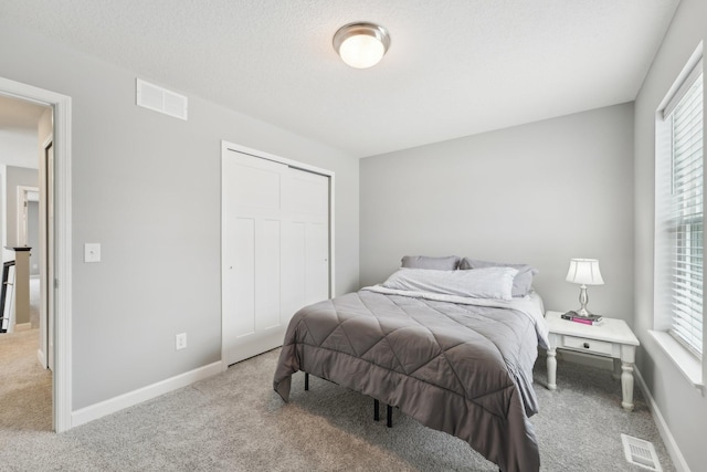 bedroom with light carpet, a closet, and a textured ceiling