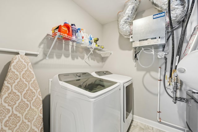 clothes washing area featuring water heater and washer and dryer