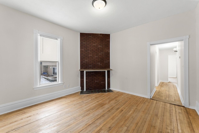 unfurnished living room with a brick fireplace and light hardwood / wood-style flooring