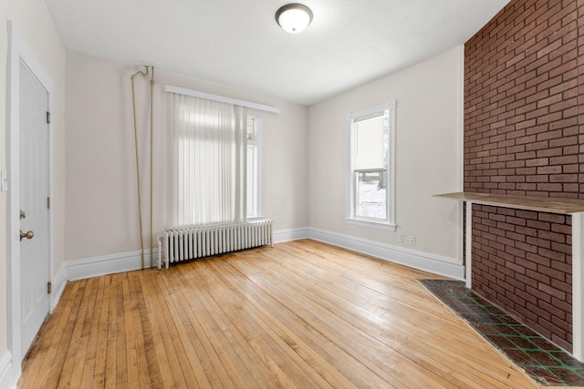 unfurnished living room with radiator heating unit and light hardwood / wood-style flooring