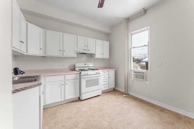 kitchen with sink, gas range gas stove, white cabinetry, cooling unit, and ceiling fan